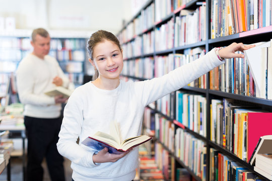 cheerful schoolgirl standing in library