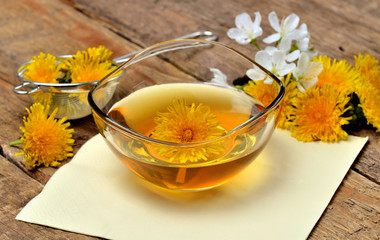 Dandelion honey in a glass bowl and dandelion head around