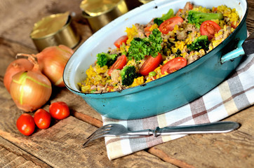 Tuna risotto with vegetables, tomatoes, broccoli and parsley in the old pan, onions, cans and oil...