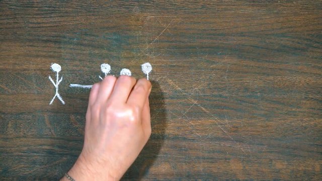 Closeup of hand draws on a wooden board. Human figures. Ahead of is the main figure.