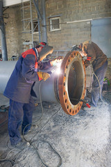 Two welders are welded, by manual arc welding, a flange DN 800 to the pipe - obrazy, fototapety, plakaty