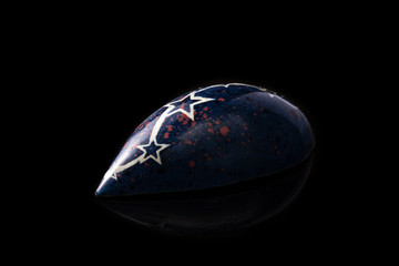 Dark blue luxury handmade chocolate candy with white stars on black background. Product concept for chocolatier