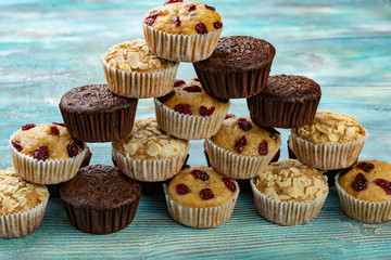 Pyramid of colorful muffins with chocolate, cherry and almonds on table.