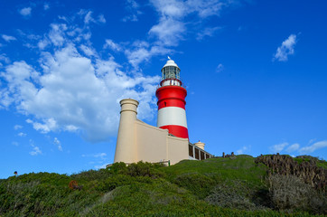 Beautiful lighthouse. Red and white lighthouse, view from bottom, blue sky with clouds on background