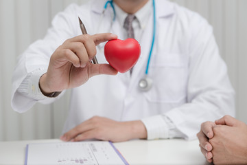 Doctor and patient are discussing something with young man patient and making notes while sitting at medical consultation.