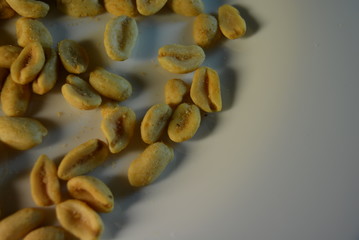 On white glass plate are peanut nuts with salt fried in yellow earth-nut, groundnut, goober, monkeynut