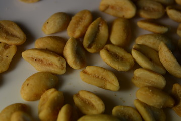 On white glass plate are peanut nuts with salt fried in yellow earth-nut, groundnut, goober, monkeynut