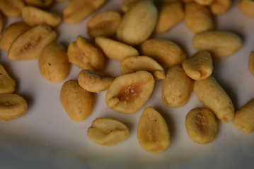 On white glass plate are peanut nuts with salt fried in yellow earth-nut, groundnut, goober, monkeynut