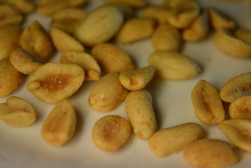On white glass plate are peanut nuts with salt fried in yellow earth-nut, groundnut, goober, monkeynut