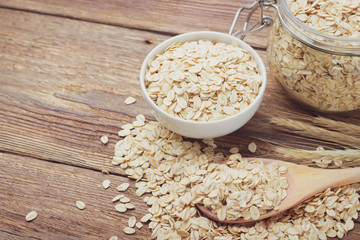 Oatmeal or oat flakes in bowl on wooden table. Toned.