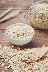 Oatmeal or oat flakes in bowl on wooden table. Toned.