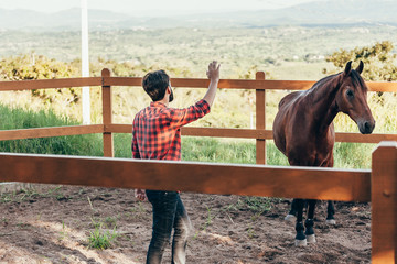 Young farmer taming horse in corral