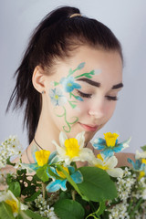 Portrait of a young girl with flowers and face art in the form of flowers on her face