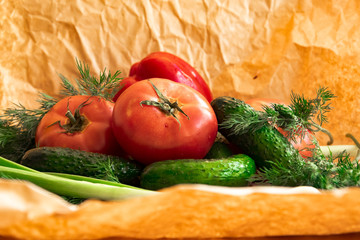 Arrangement  on the wrapping paper of a assortment of fresh vegetables, red pepper, garlic, green onions, tomatoes, cucumbers