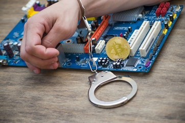 hand in handcuffs holding bitcoin on the board. Closeup