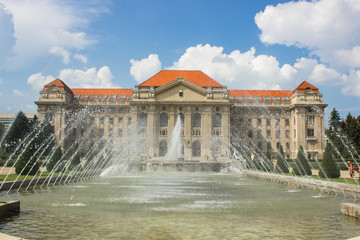 colorful university campus facade in bright summer day in outdoor park with small trees and fontain