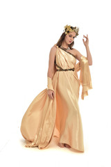 full length portrait of brunette woman wearing long golden grecian gown, standing pose. isolated on white studio background.