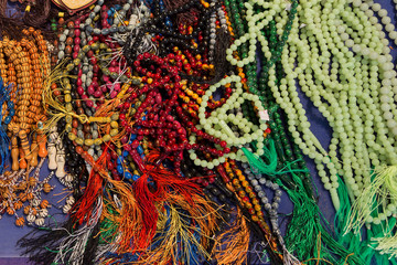 Multicolored lot of tasbeeh Tasbih beads. Huge amount of muslim prayer beads layeing on the table. Selling tasbeehs. Open air market trading with prayer beads.