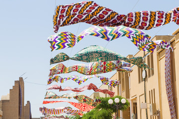 Waving in sky fabric. Multicolored silk textile materials fluttering against the blue sky. Garland of bright colored developing in the wind silk fabric materials against the sky.