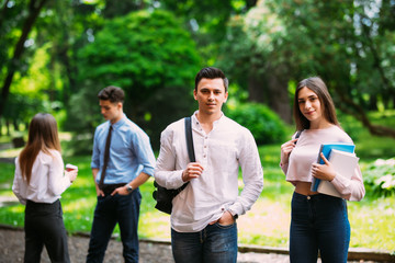 Young college friends talking while walking at campus in front of friends