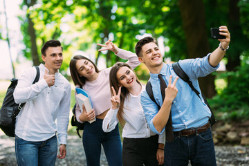 Cheerful young friends take selfie themselves near university campus outdoors