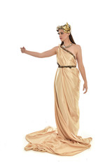 Fototapeta premium full length portrait of brunette woman wearing long golden grecian gown, standing pose. isolated on white studio background.