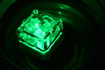 In a glass of champagne glass floats a green ice cube very stylish and beautiful