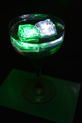 In a glass glass from under the champagne floats a green ice cube and a white ice cube is very stylish and beautiful