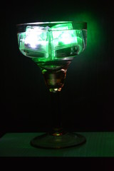 In a glass glass from under the champagne floats a green ice cube and a white ice cube is very stylish and beautiful