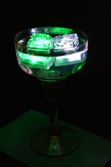 In a glass glass from under the champagne floats a green ice cube and a white ice cube is very stylish and beautiful
