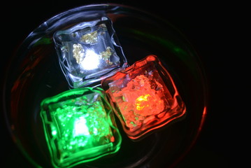 In a glass of champagne float white, red and blue ice cubes brightly and festively