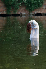 Mysterious Nymph dressed with withe dress walking in water