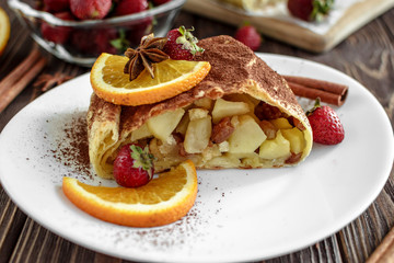 Homemade strudel with apples on a wooden background