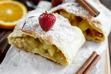 Homemade strudel with apples on a wooden background