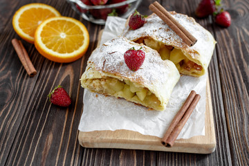 Homemade strudel with apples on a wooden background