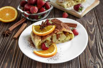 Homemade strudel with apples on a wooden background