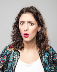 Portrait of surprised young woman against grey background