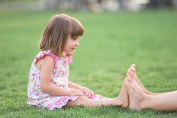 Little girl measuring her tiny feet with her older sister