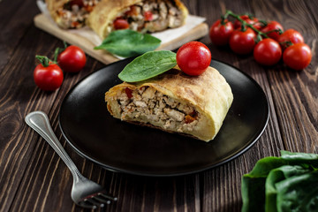 Homemade strudel with meat on a wooden background