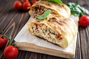 Homemade strudel with meat on a wooden background