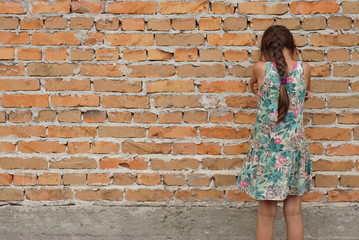 Fototapeta na wymiar lonely sad girl on the background of a brick wall
