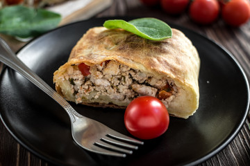 Homemade strudel with meat on a wooden background