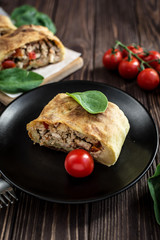 Homemade strudel with meat on a wooden background