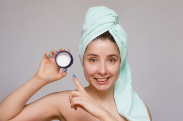 Woman showing by index finger on a jar with cream of facial mask in her hands. Skin care treatment concept.