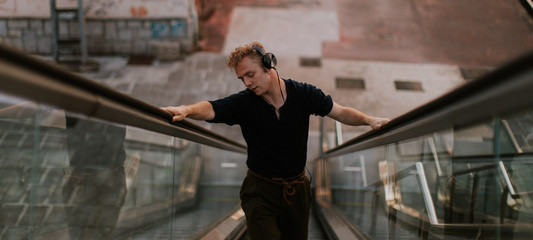 man listening to music and dancing while go up on mechanical stairs