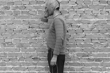 A man in a gas mask against a brick wall is black and white