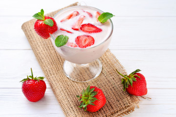 Homemade yogurt with fresh red strawberry on a wooden background. Top view.