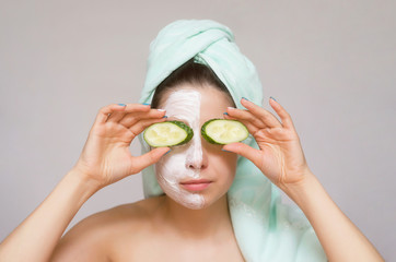 Woman holding in hands a slices of cucumber in frint of her eyes likes a binoculars. Naturotherapy and face skin care concept.