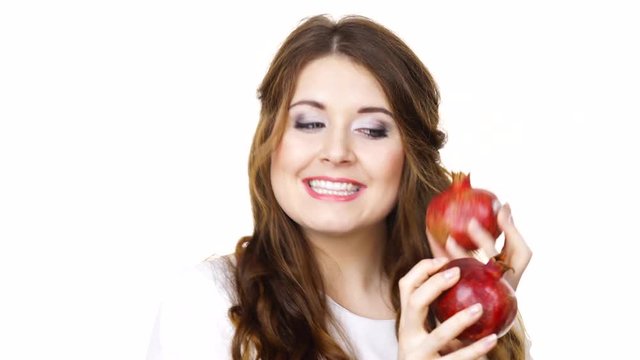 Joyful young woman playing with pomegranate fruits, isolated on white. Healthy eating, cancer prevention, immune support concept