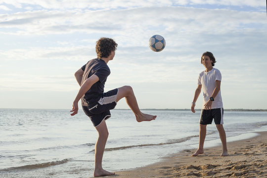 Teenage boys playing soccer on the beach